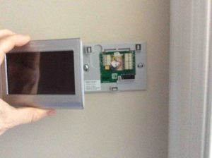 Picture of the Honeywell RTH9580WF internet thermostat. Snapping it onto wall plate.
